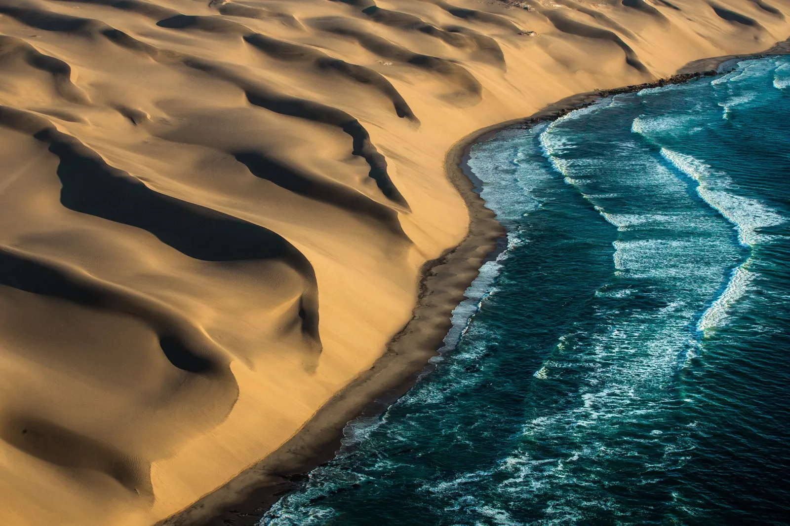 Dunas do deserto encontrando o oceano na Namíbia